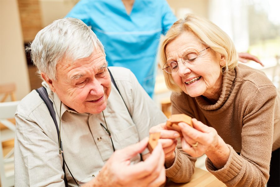 Two older adults socializing and working on a puzzle.