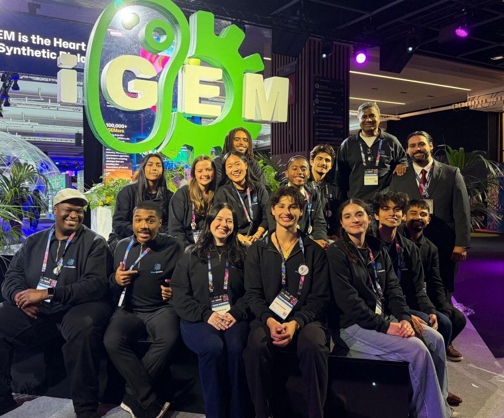 Thirteen students from the team, one student adviser and two principal investigators dressed in black pose at the iGEM Grand Jamboree.