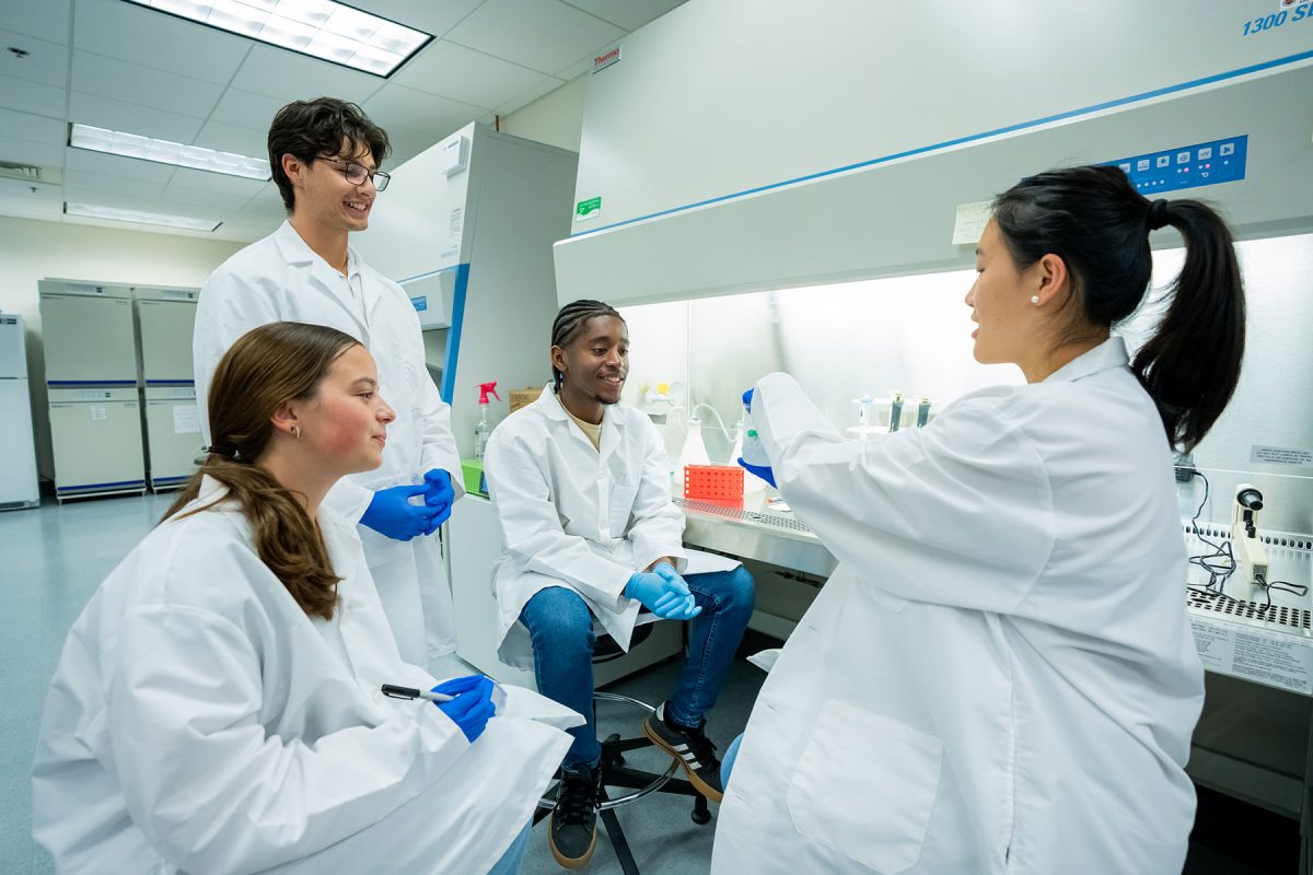 Students in white coats in a lab.