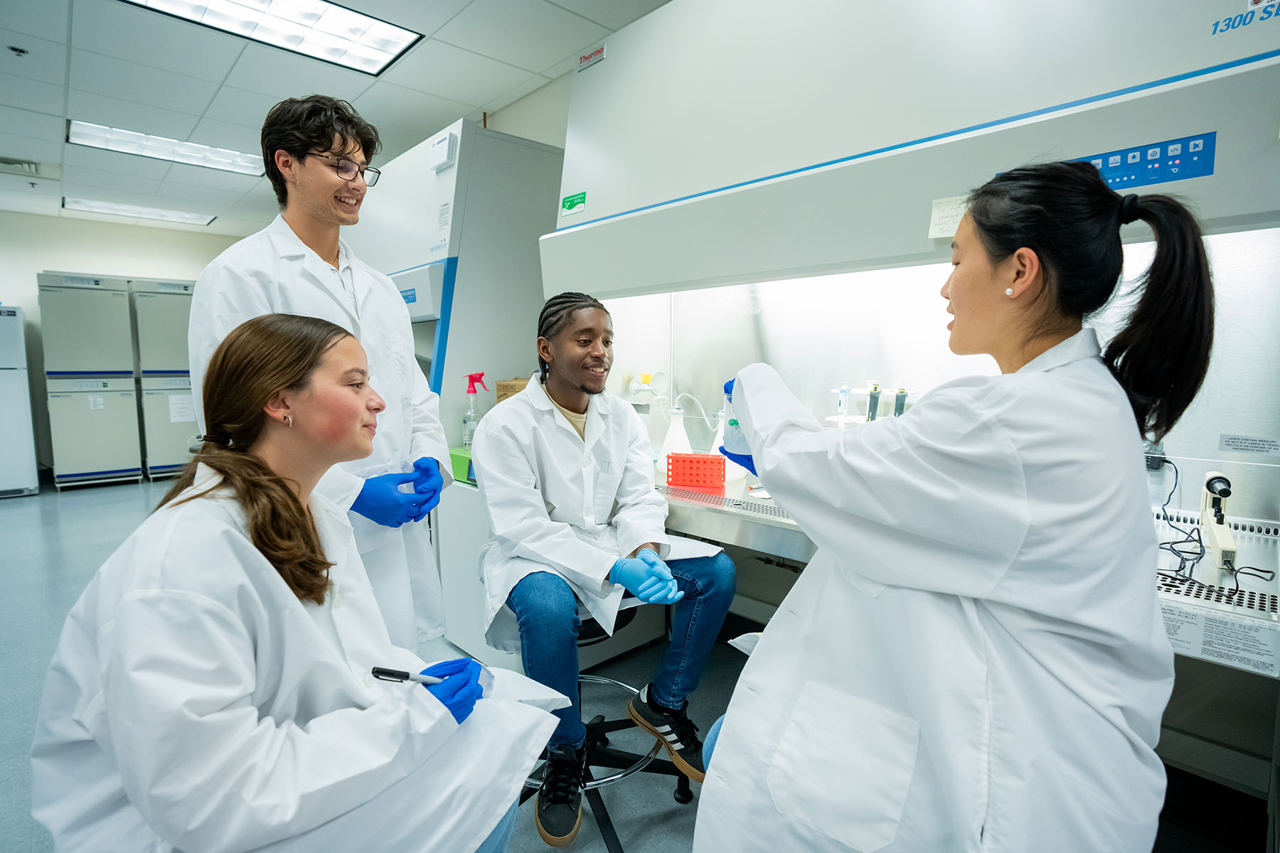 Students in white coats in a lab.