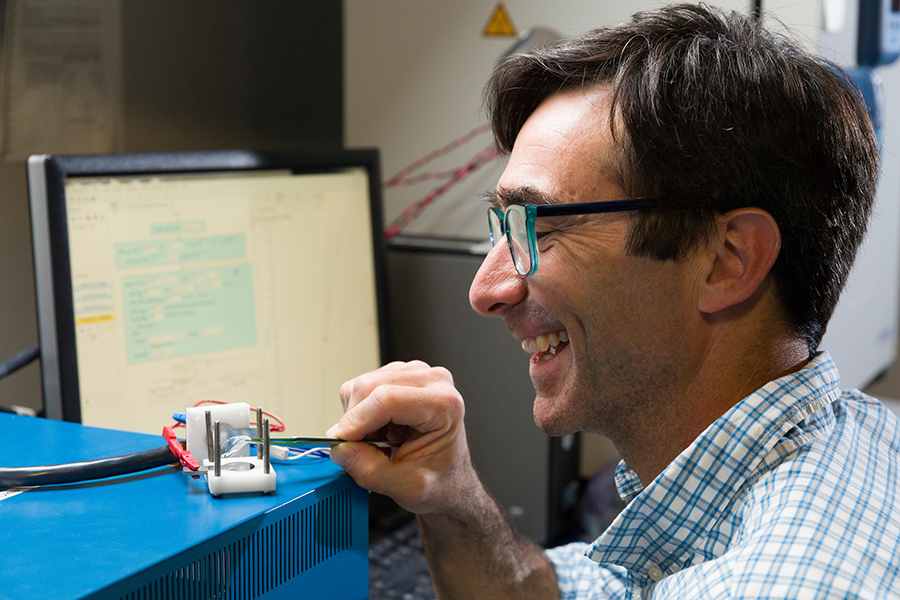 A smiling man works with polymers in an engineering laboratory.
