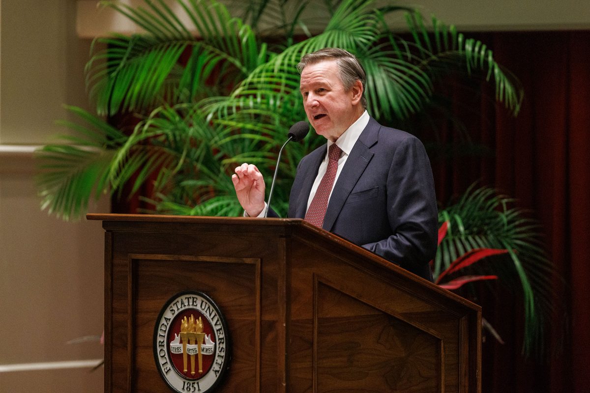 FSU President Richard McCullough at a podium in front of a palm tree in the College of Medicine auditorium.