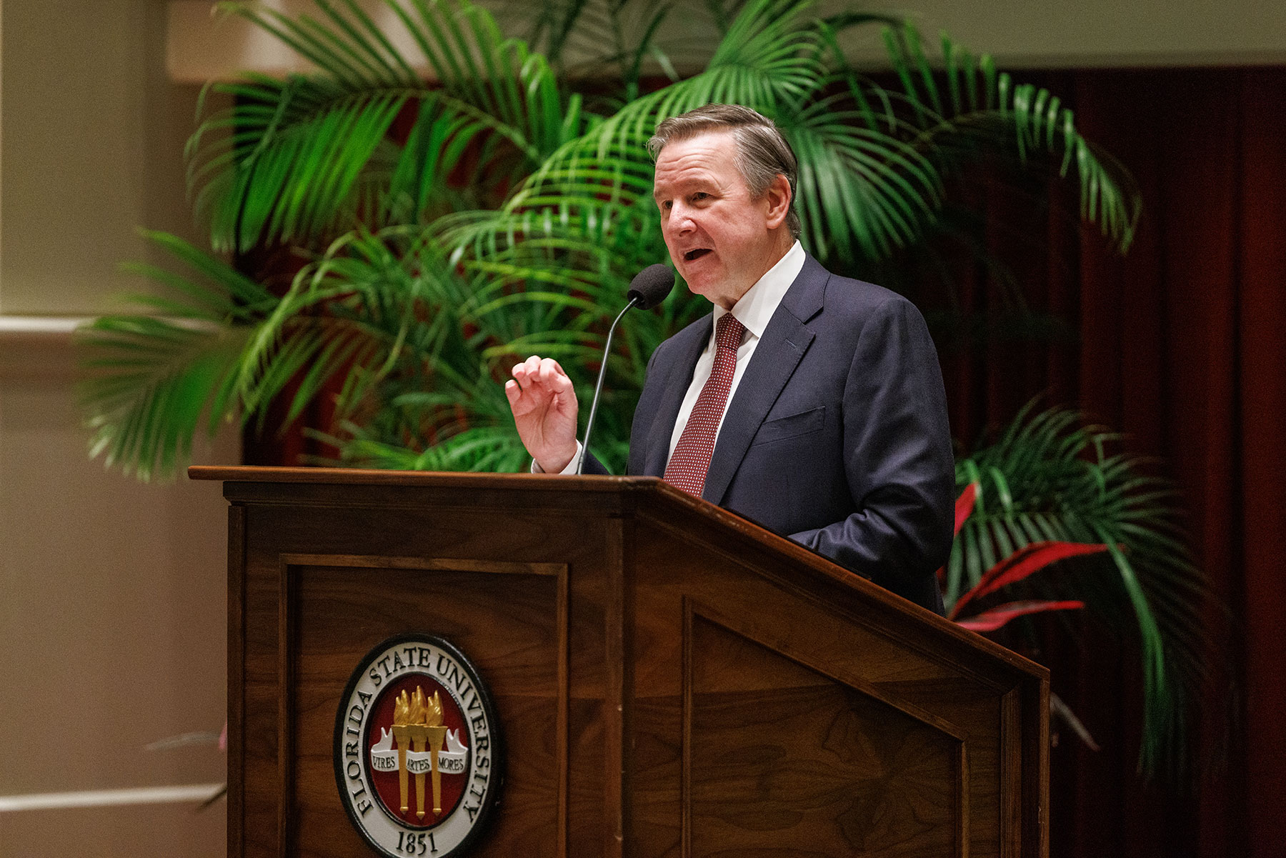 FSU President Richard McCullough at a podium in front of a palm tree in the College of Medicine auditorium.