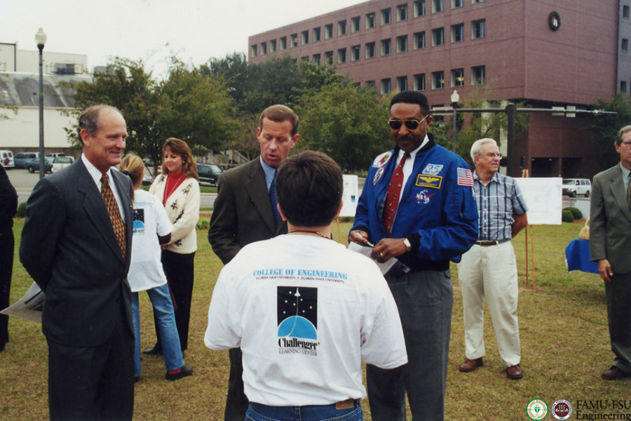 A group of people stand on a small grassy field in downtown Tallahassee.