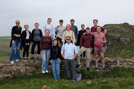 Honors Global Experiences in London Summer 2025 students and Honors Professor Michael Furman pose atop the remains of Hadrian's Wall as part of a three-mile hike along the wall to Housesteads Roman Fort during an overnight excursion.