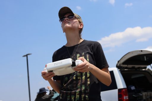 A female student in a hat holds a drone remote controller