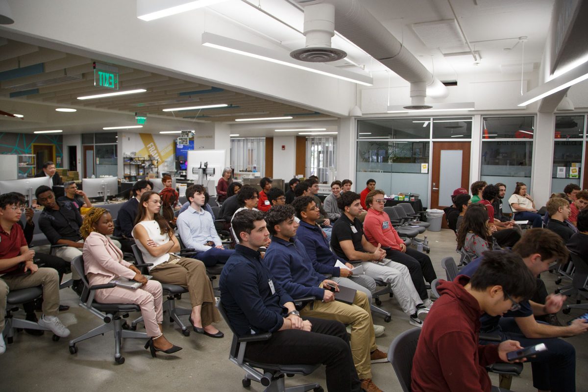 Many students sit in chairs looking forward.