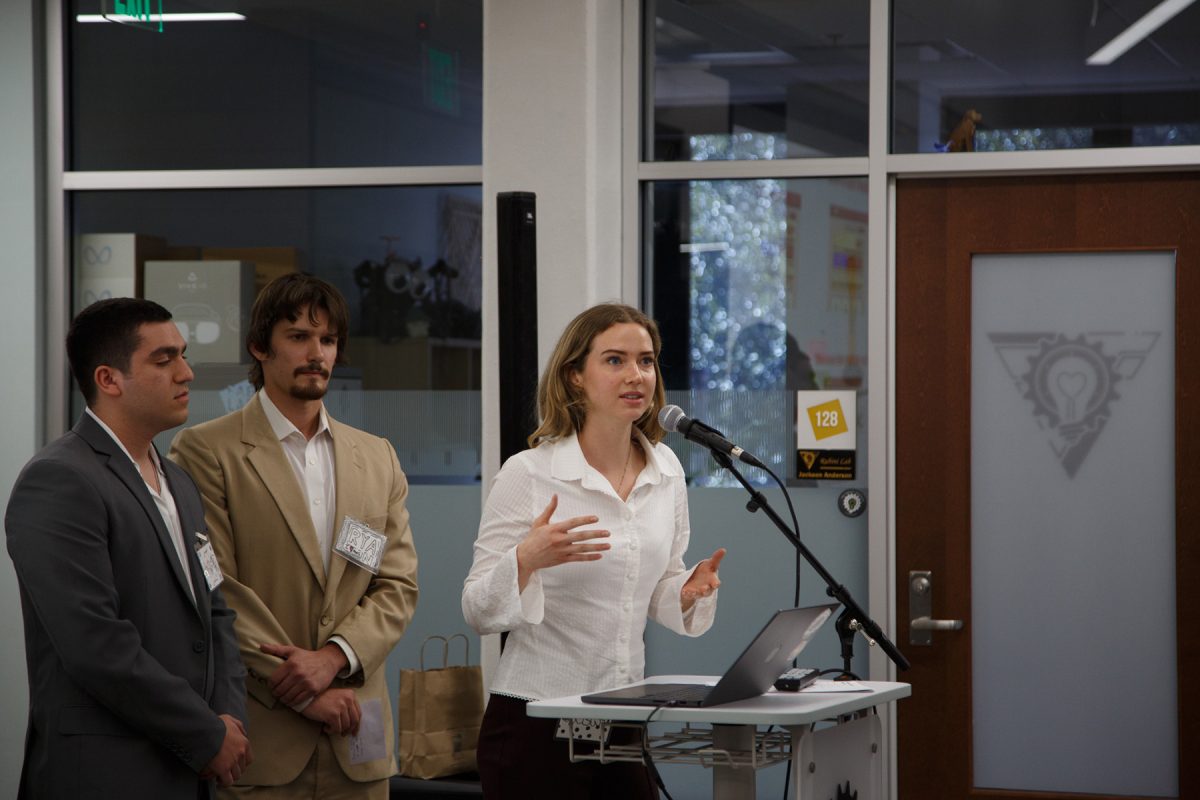 A student speaks into a microphone at a podium, with a student standing behind them.