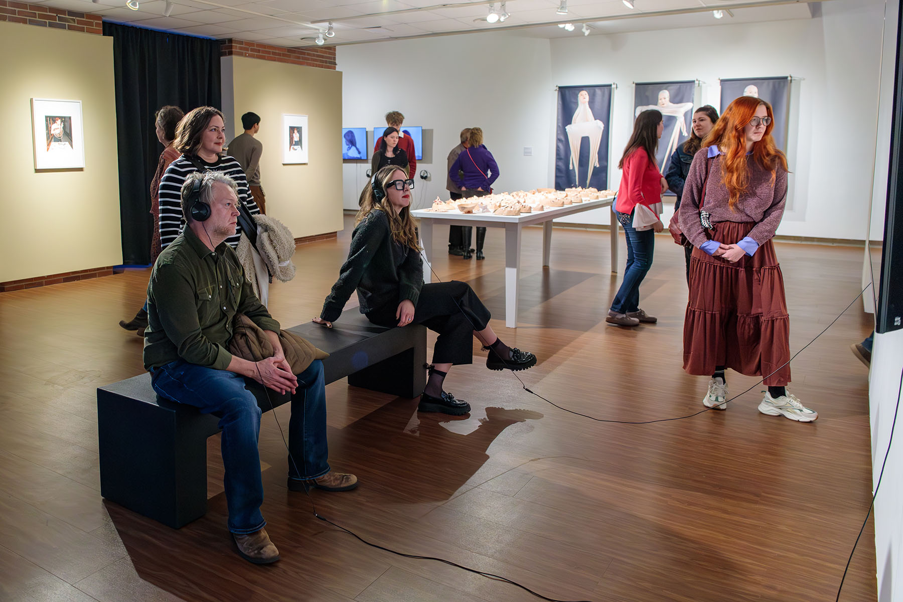 A group of visitors explores the various photography, sculpture and video installations during the spring exhibition opening at the Museum of Fine Arts. (College of Fine Arts)