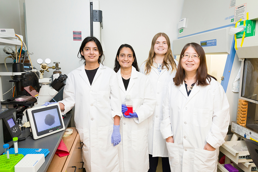 Four women in lab coats stand in a science lab.