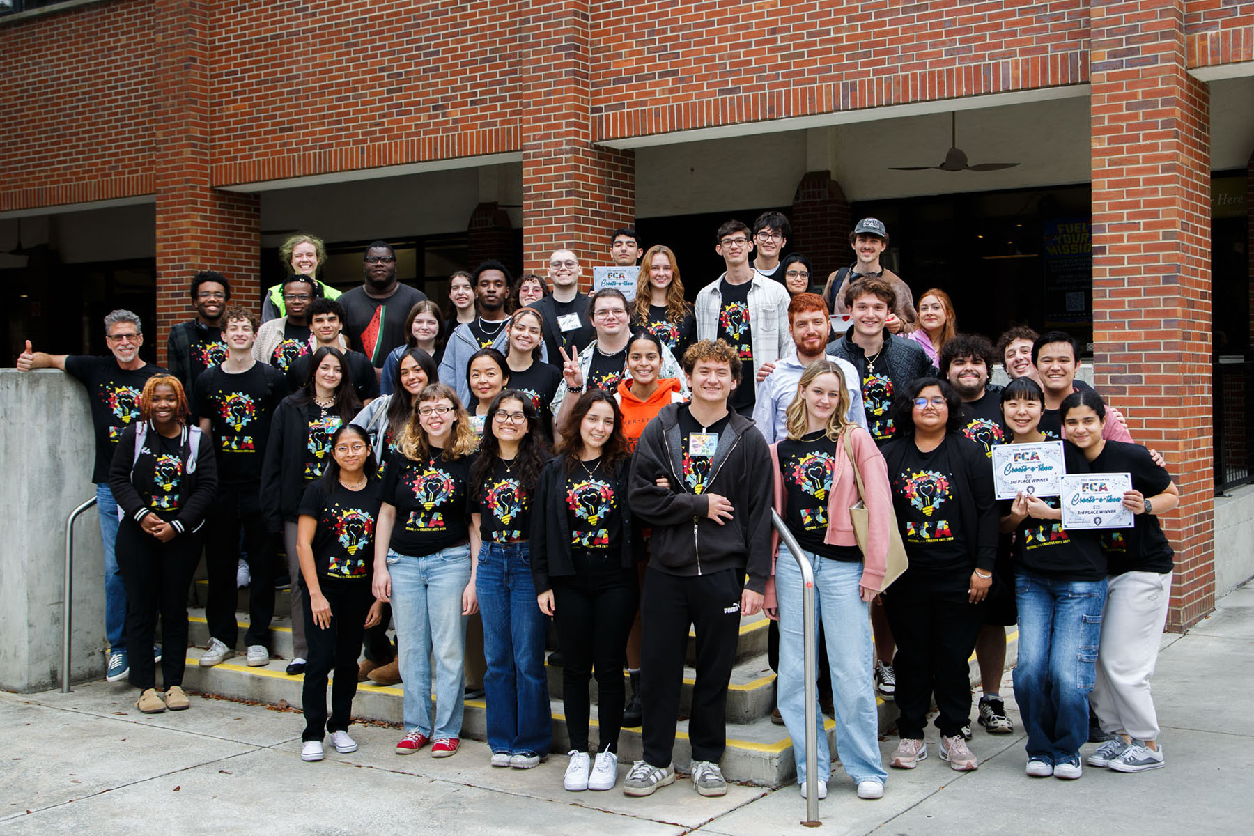 Students wearing Innovation hub T-shirts pose for a picture on stairs