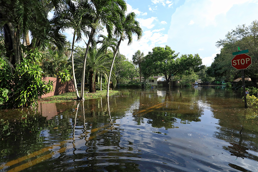 An intersection in a residential neighborhood flooded with rainwater.