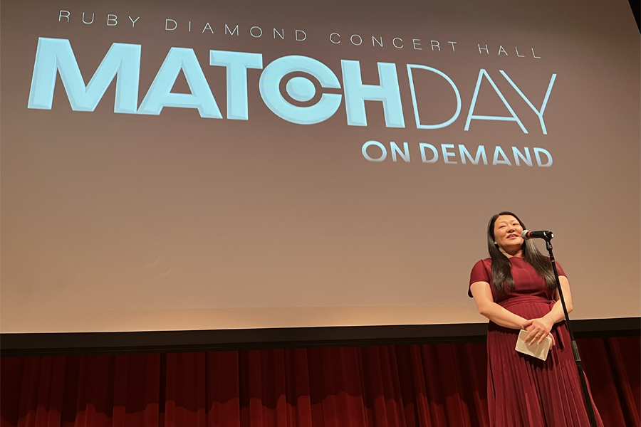 Woman speaks into a microphone in front of a screen