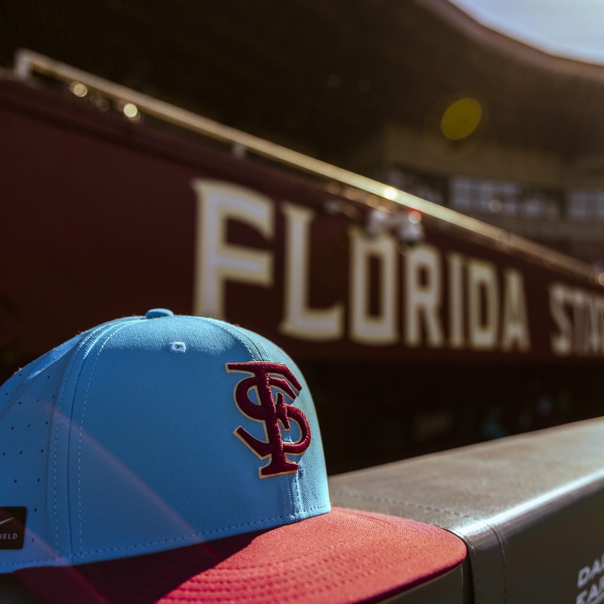A closeup of a blue and red FSU baseball hat sitting on a ledge at a stadium