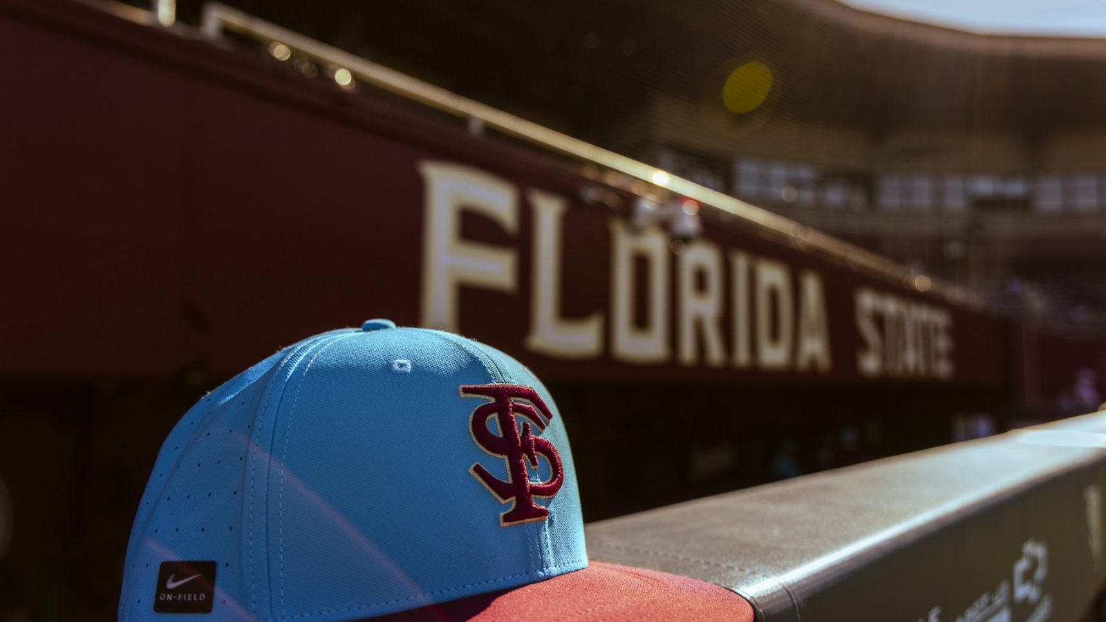 A closeup of a blue and red FSU baseball hat sitting on a ledge at a stadium
