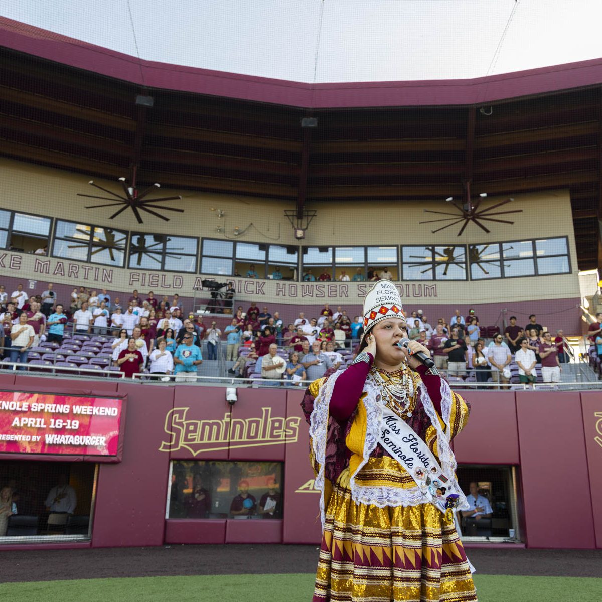 Woman in indigenous clothing sings at a seminoles stadium
