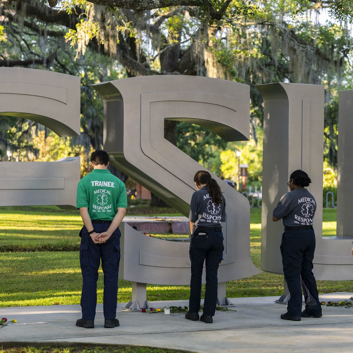 People stand In reflection in front of the FSU letters outside the student union.