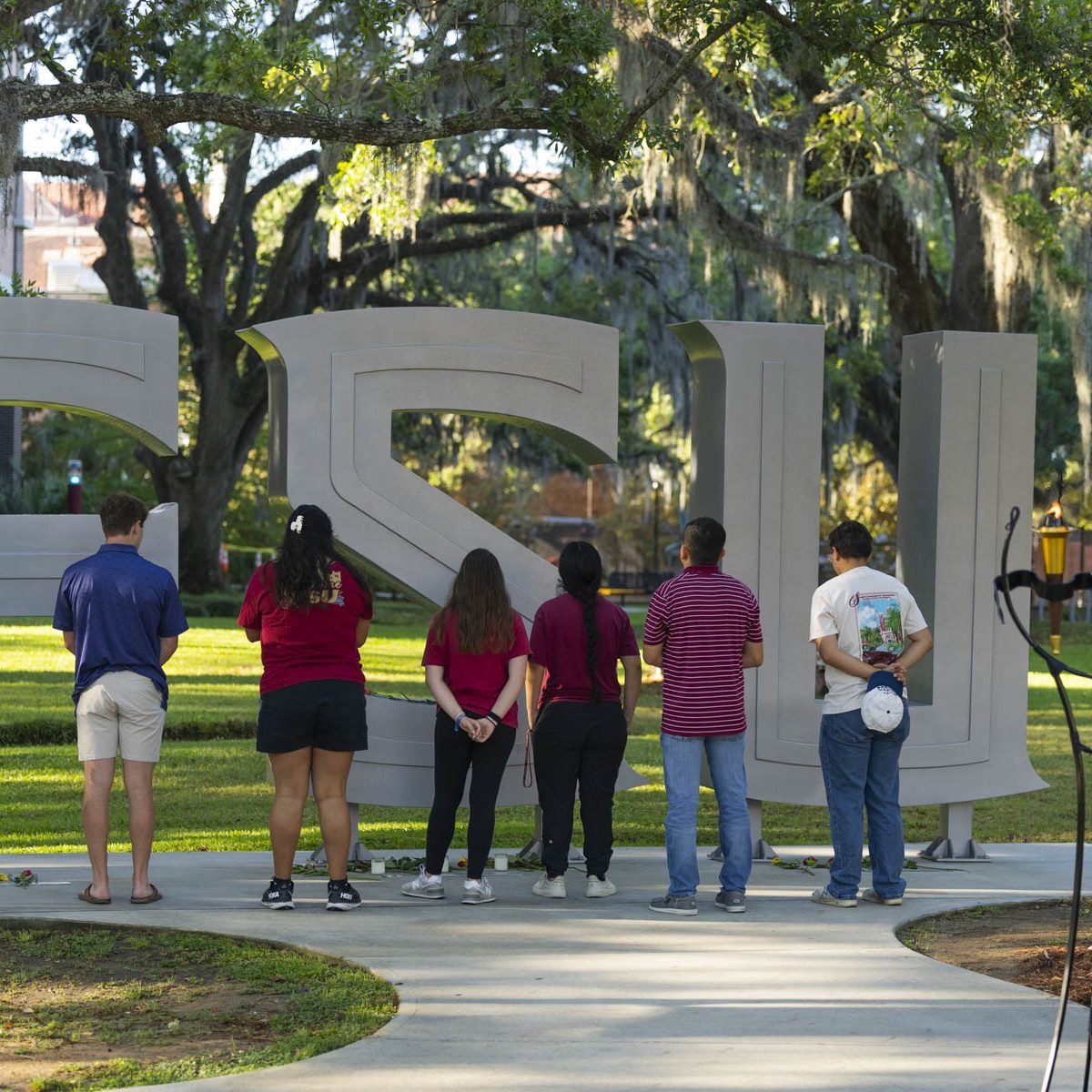 People placing flowers and stand In reflection in front of the FSU letters outside the student union.
