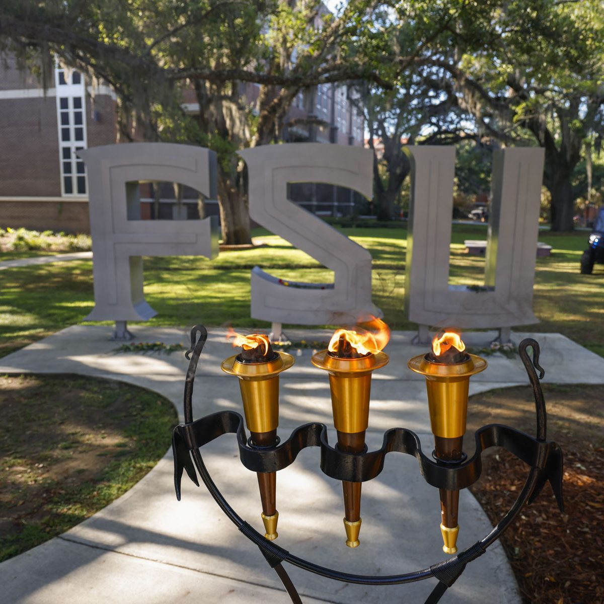 The FSU ceremonial torches are lit and placed in front of the fsu letters outside the student union