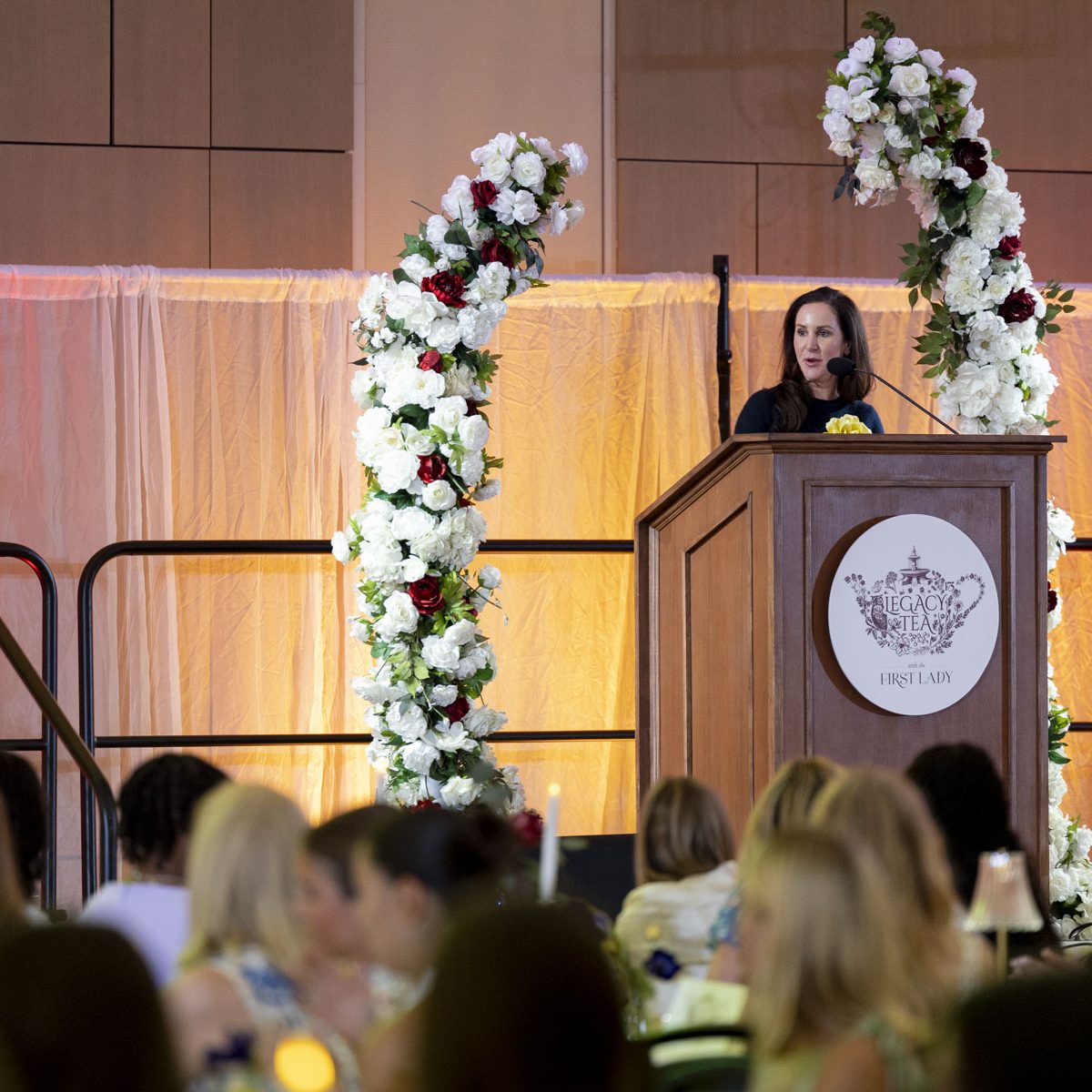 person speaking at the podium to a large room