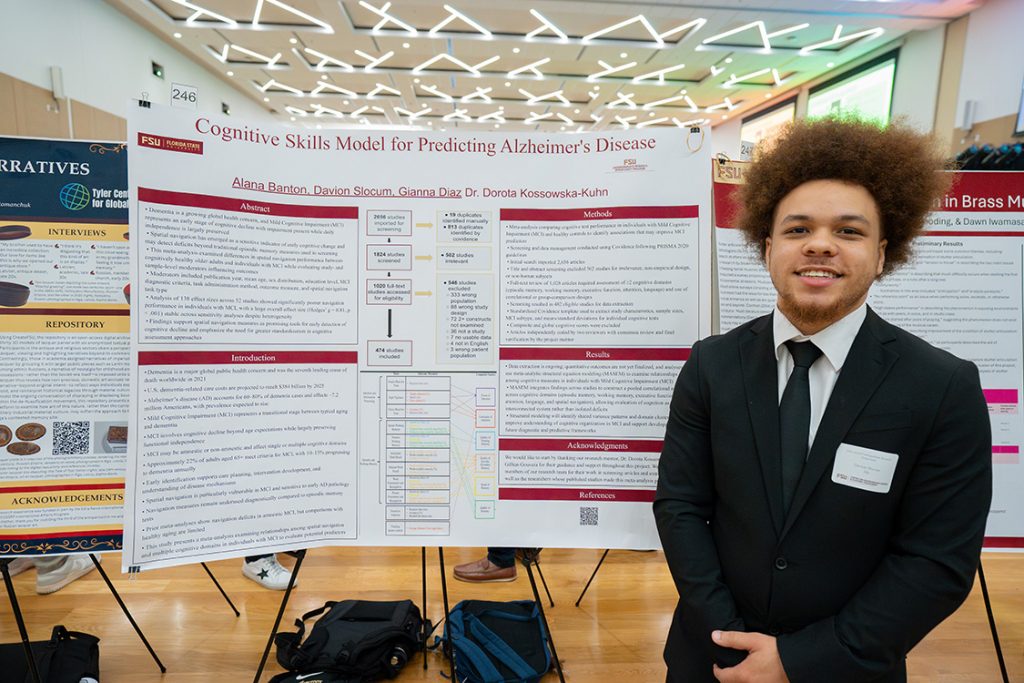 A student stands in front of a research poster with the title "Cognitive Skills Model for Predicting Alzheimer's Disease."