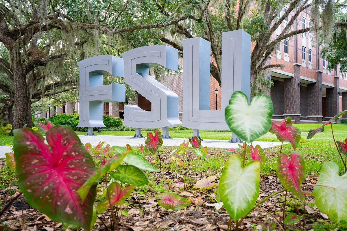 Large silver “FSU” letters stand on a landscaped campus lawn