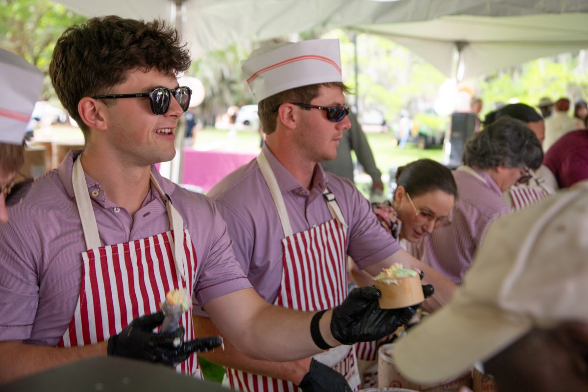 Two students wearing red and white striped aprons serve ice cream