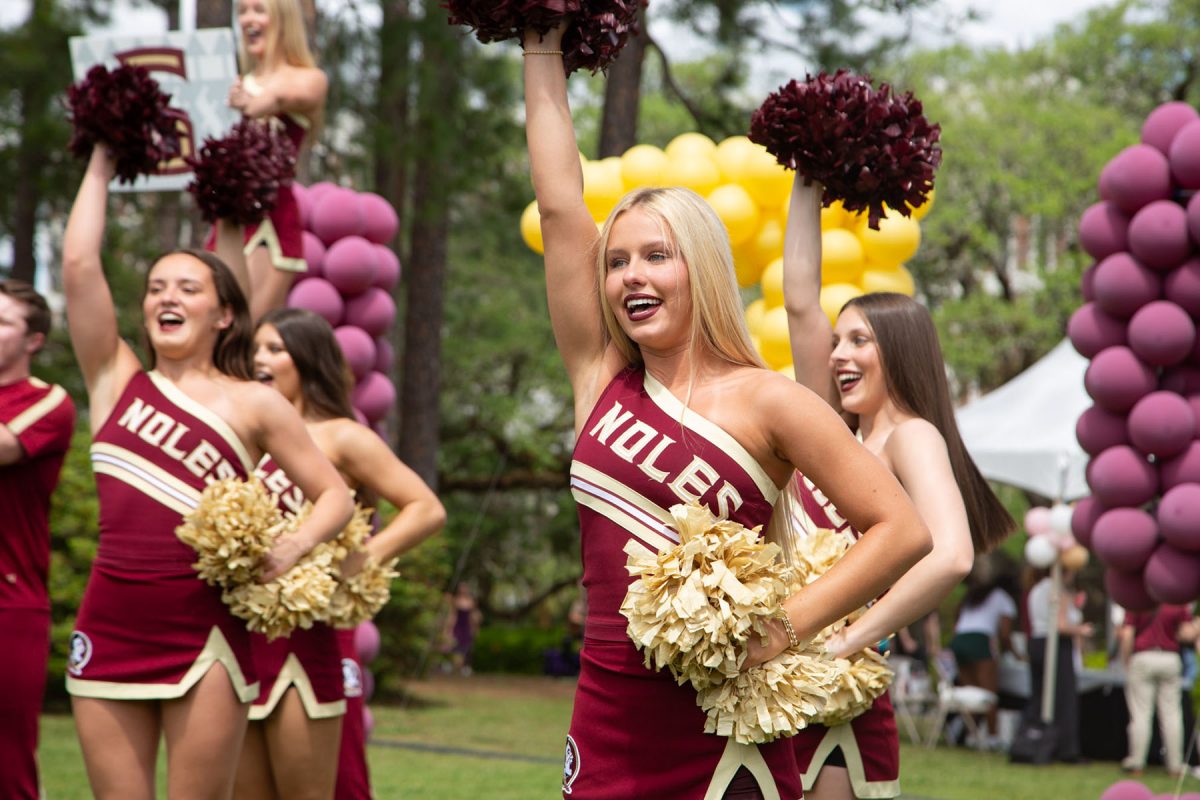 A cheerleader, dressed in garnet and gold, puts one hand in the air and one on her hip