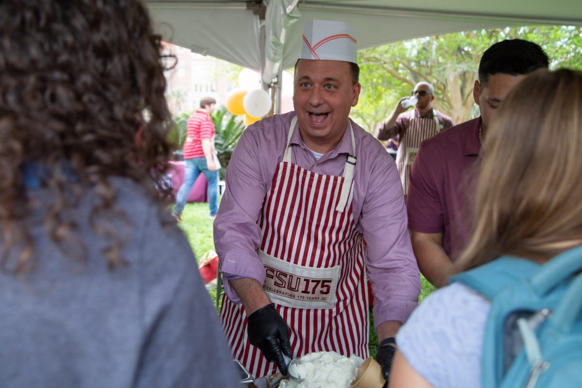 A man wearing a red and white striped apron and a hat smiles with his mouth agape