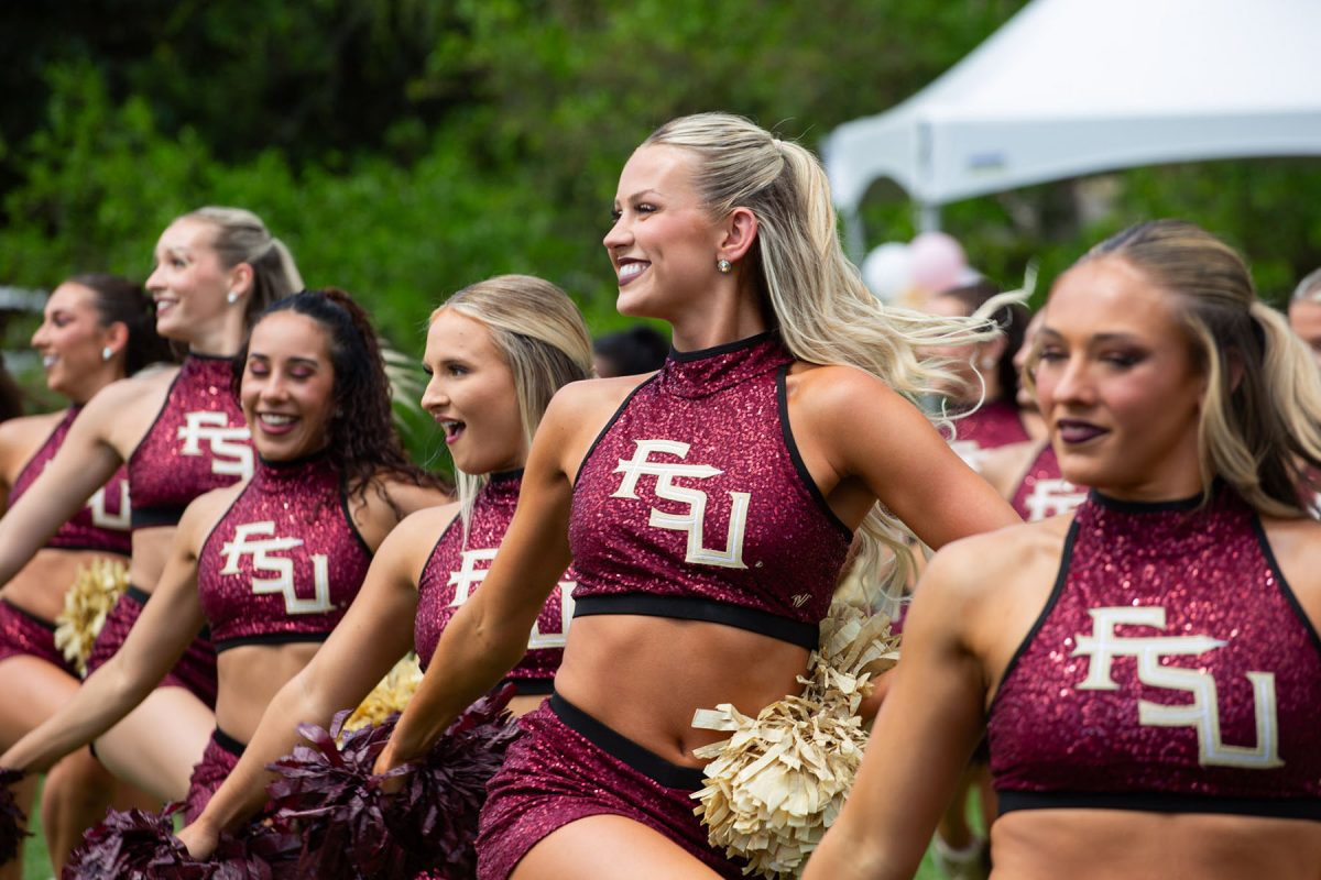 Dancers wearing sparkly red FSU uniforms, smile and do their routine