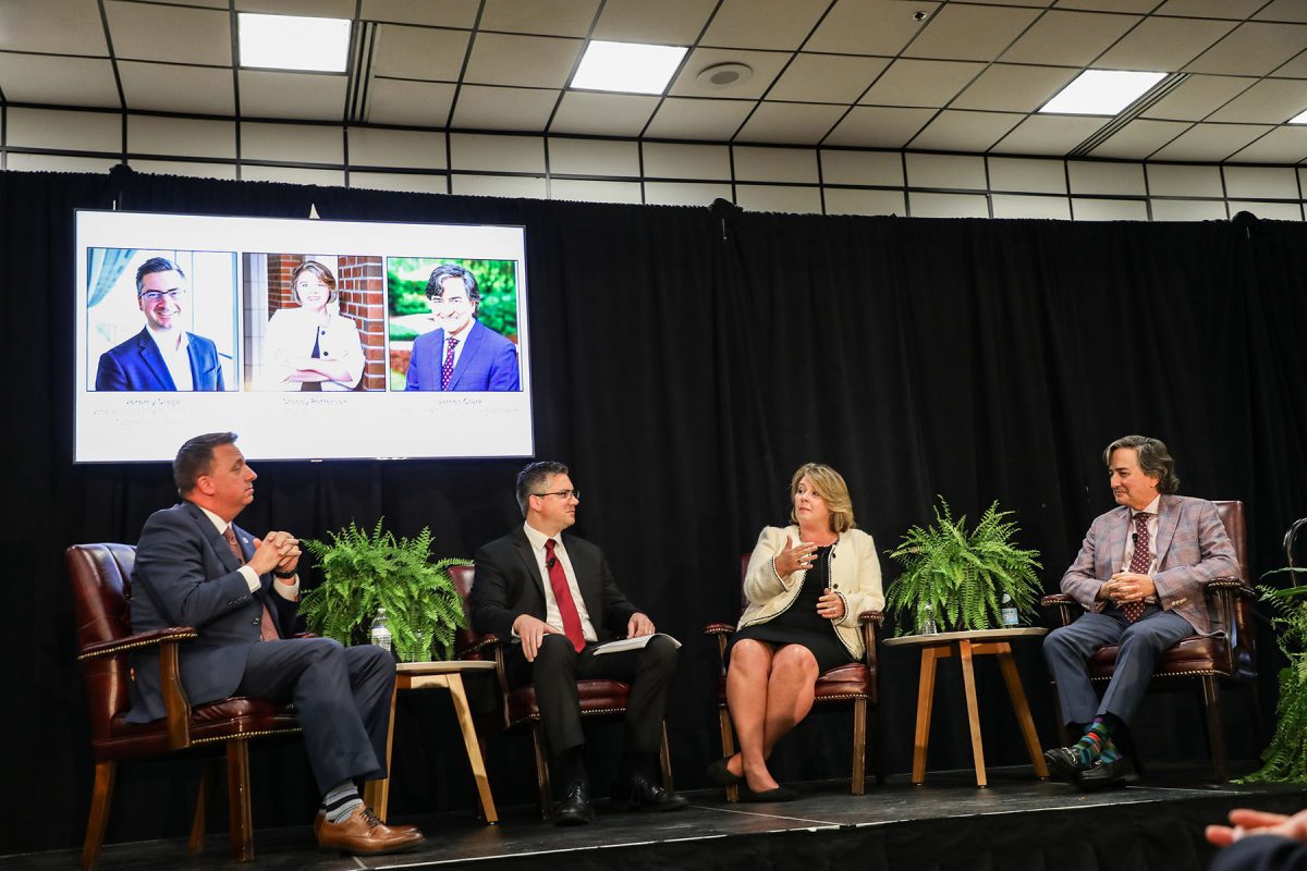 Four individuals sitting on a stage during a panel discussion.