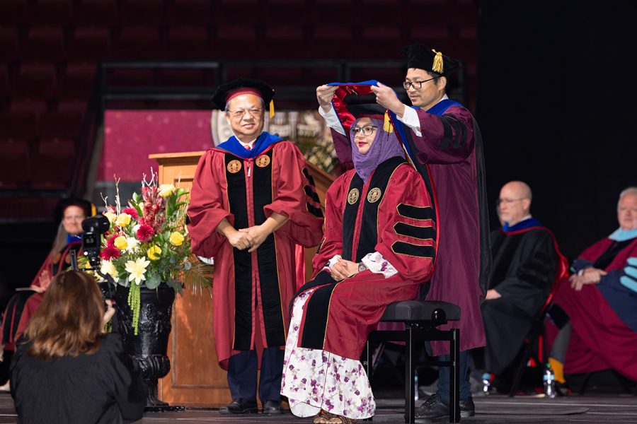 A female doctoral student is hooded by their faculty mentor.
