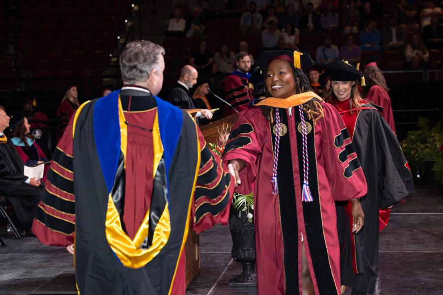 FSU President Richard McCullough shakes a black female doctoral graduate's hand.