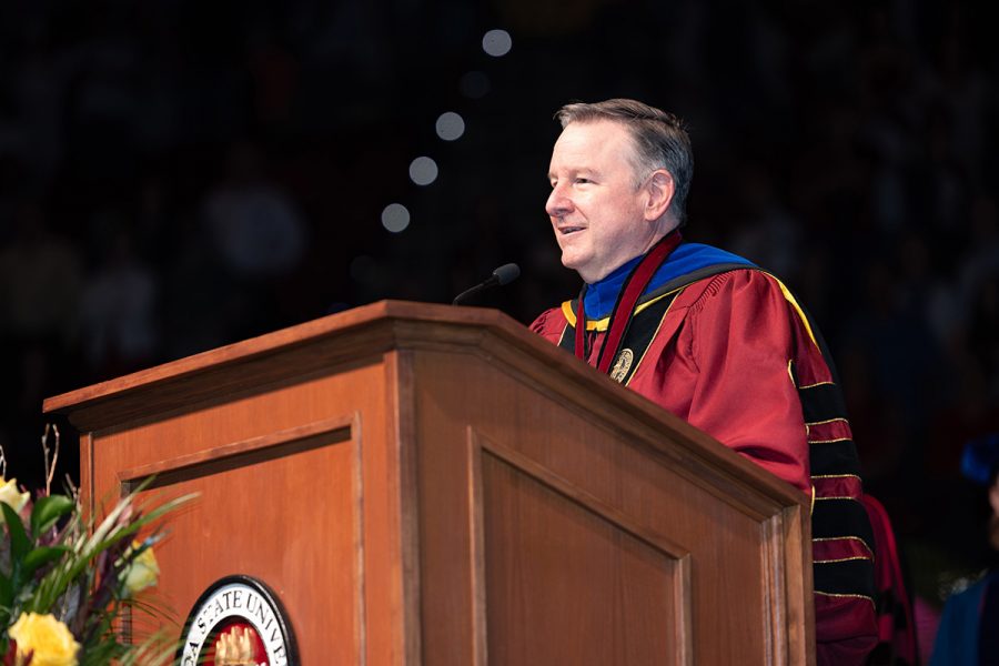 President Richard McCullough speaks at a wooden lectern during a commencement ceremony.