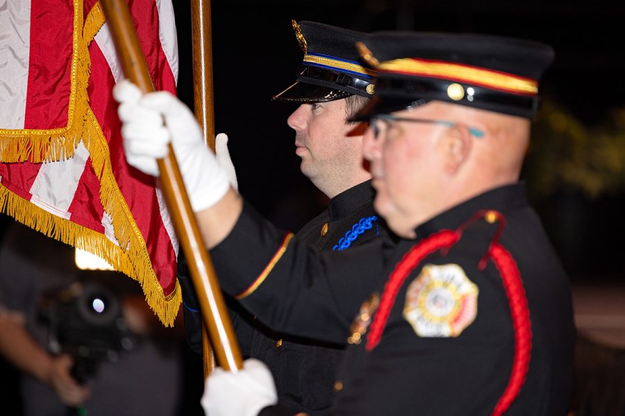 Two men stand at attention while holding an American flag during commencement.