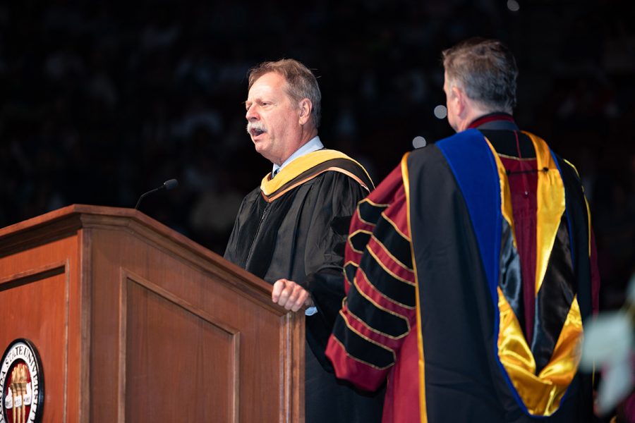 Graduate School Dean Steve McDowell and President Richard McCullough stand at a wooden lectern during commencement.