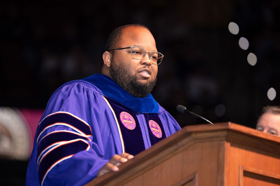 Dean of undergraduate studies DeOnte Brown speaks from a wooden lectern during a graduation ceremony.