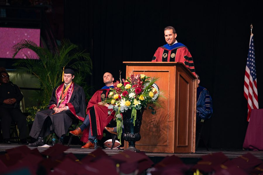 Daniel Perez speaks from the podium with flowers on the stage during Florida State University’s commencement ceremony.