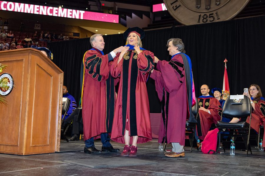 Sara Blakely stands on stage as an honorary hood is placed over her shoulders by President Richard McCullough and Provost Jim Clark.