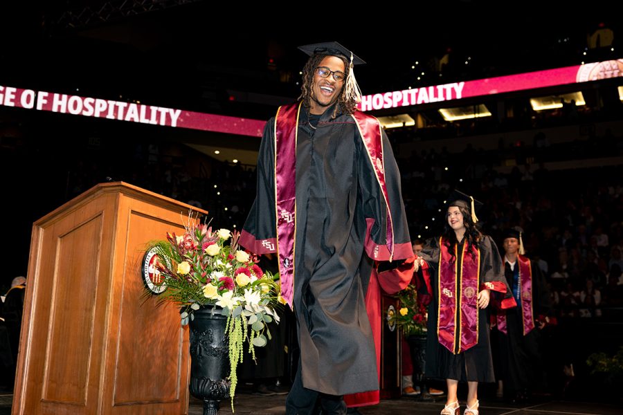 A graduate walks across the stage during commencement.