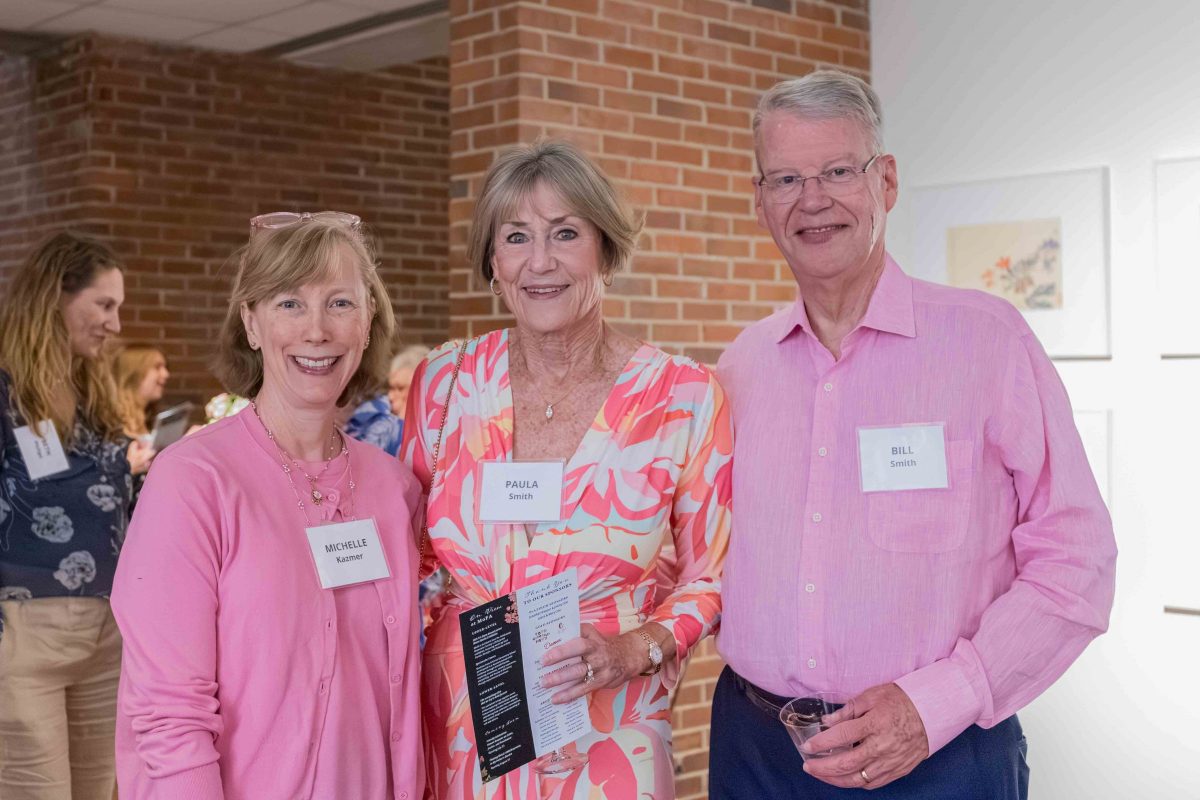 Two women and a man pose for a photo while attending Art in Bloom.
