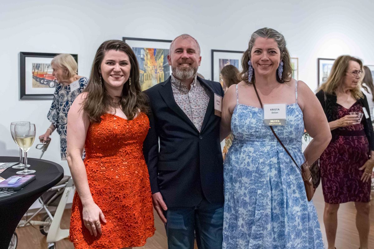 A group of two women and a man smile at the camera as they attend MoFA's Art in Bloom event.