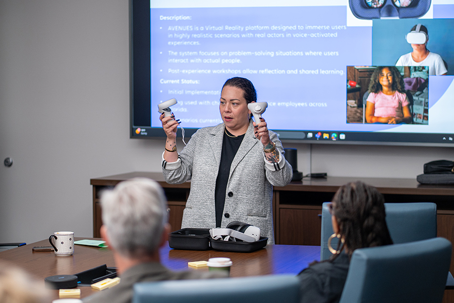 A person holds virtual reality equipment and explains how they function to support virtual social worker training.