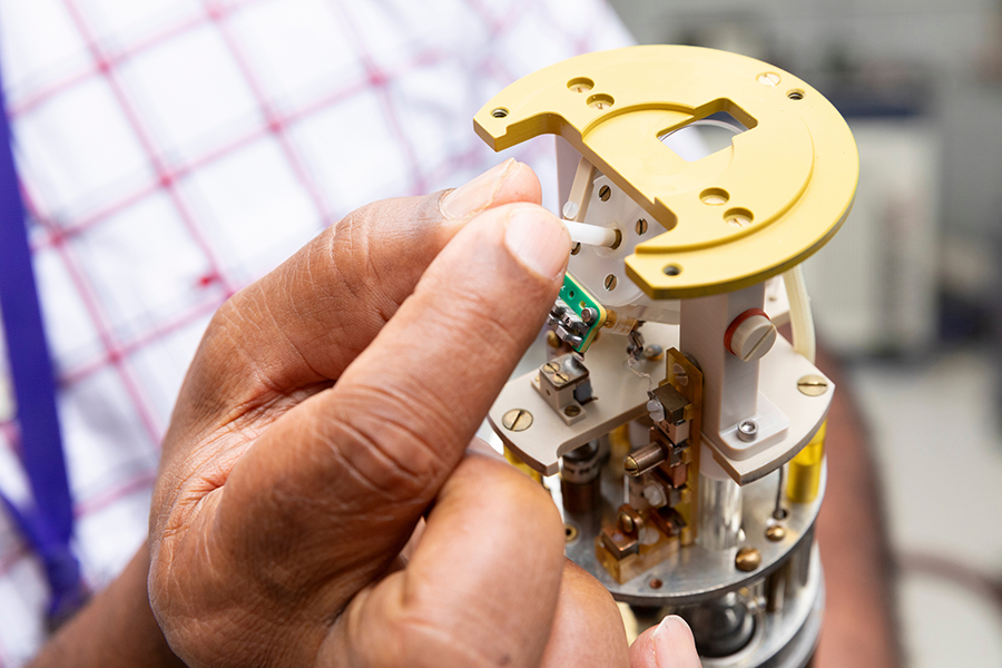 Close-up view of a researcher’s hand inserting a small component into a lab instrument.