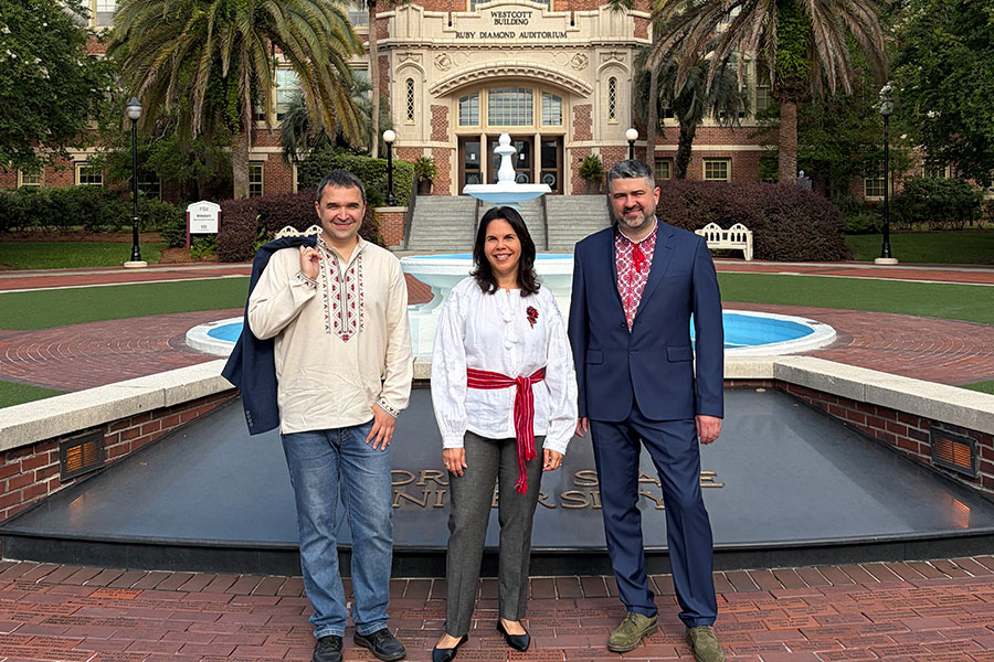 Three people standing in front of the Westcott fountain and building.