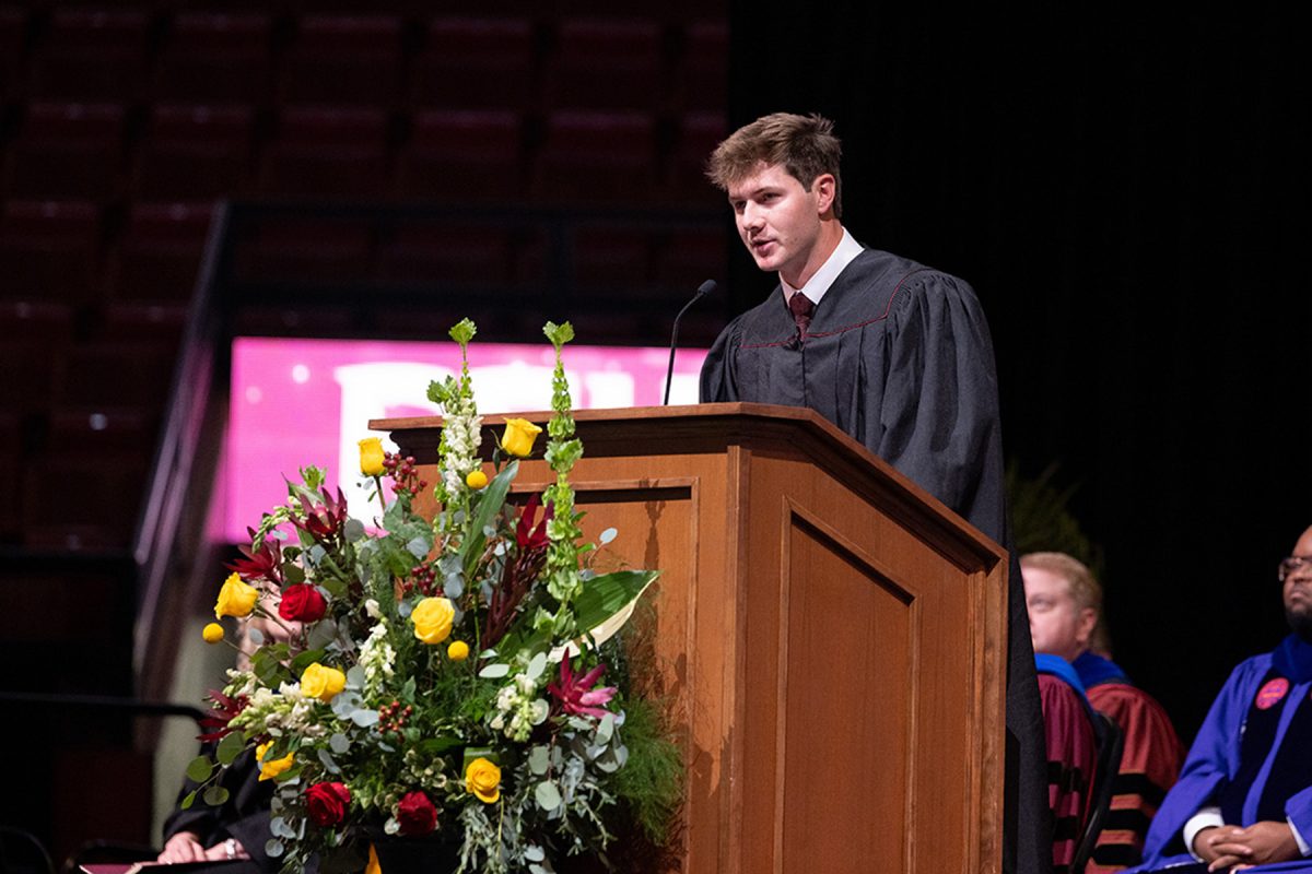 FSU Student Body President Ian Seibert addresses the crowd from a floral-decorated podium during the commencement ceremony.