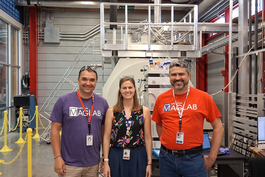 Three people standing in front of magnet equipment.