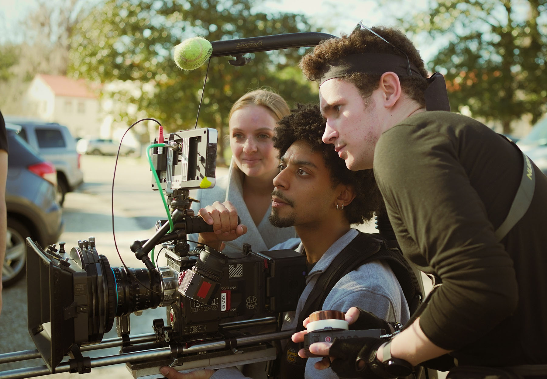 Three Florida State University film students gather around a professional digital cinema camera, reviewing footage on a monitor during an outdoor film production.