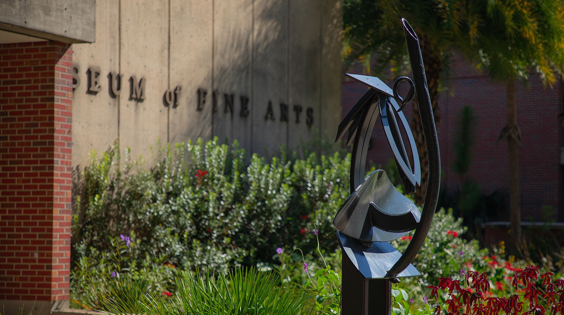A black metal abstract sculpture by Ed Love stands in a garden outside the FSU Museum of Fine Arts.