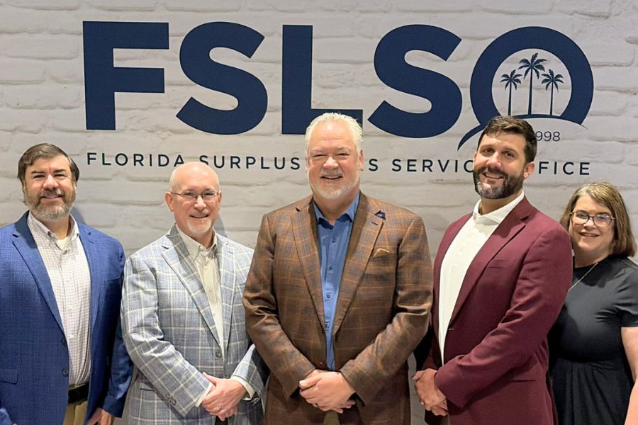 Five individuals pose in front of the FSLSO logo.